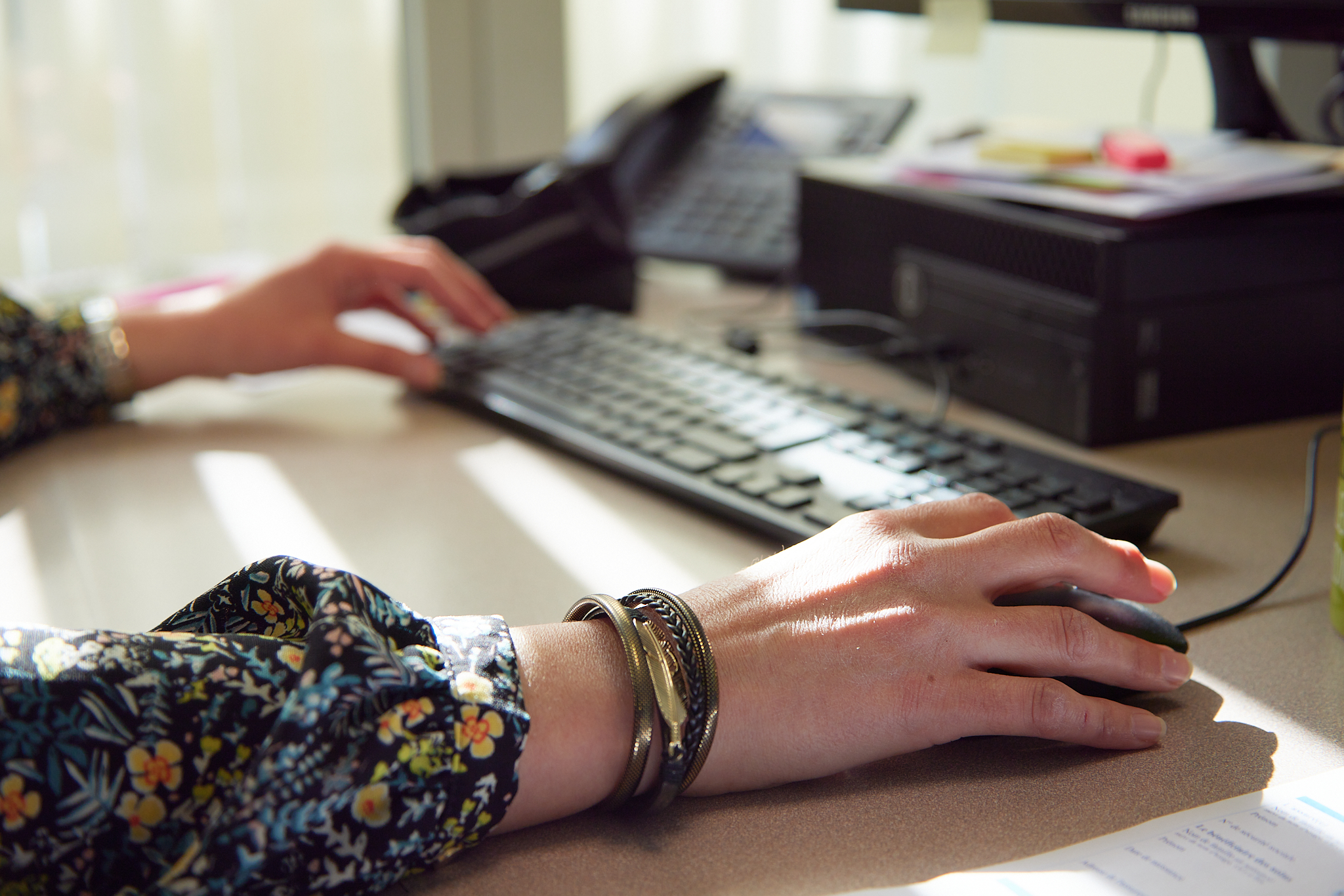 Image d'une personne assise à son bureau qui tape sur le clavier de son ordinateur portable et utilise la souris de l'autre main